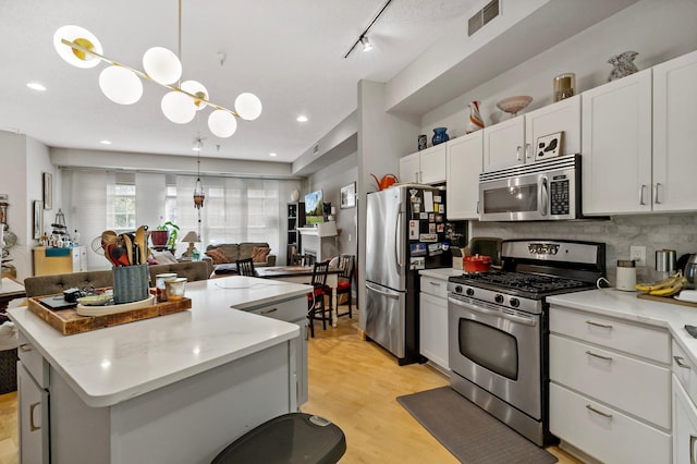 kitchen with a kitchen island, visible vents, white cabinets, open floor plan, and appliances with stainless steel finishes