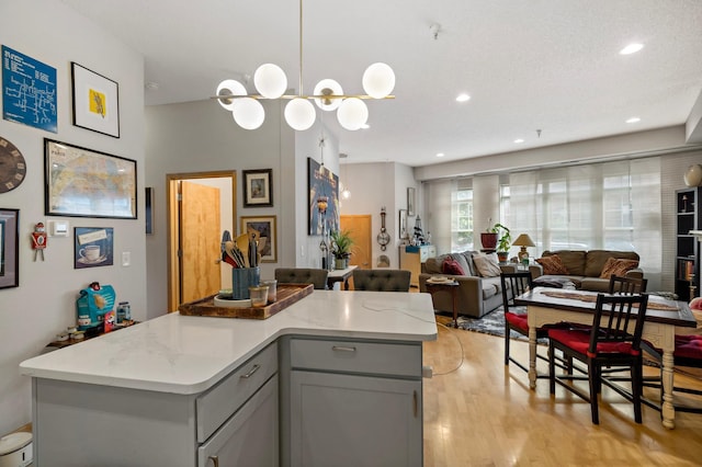 kitchen with open floor plan, a center island, gray cabinets, light wood-style floors, and recessed lighting