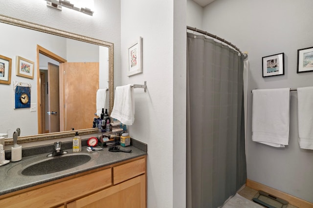 full bathroom featuring a shower with shower curtain, baseboards, and vanity