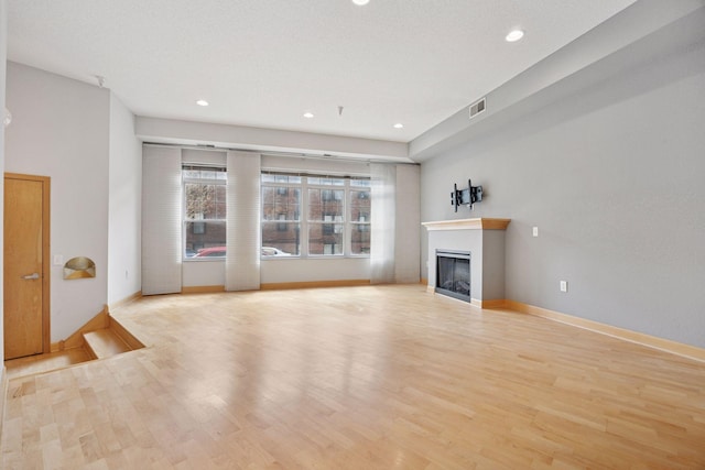 308 18th St Unit 101, Minneapolis, MN 55404 - unfurnished living room featuring a glass covered fireplace, visible vents, recessed lighting, wood finished floors, and baseboards