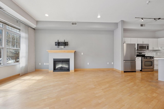 308 18th St Unit 101, Minneapolis, MN 55404 - unfurnished living room with light wood-style flooring, a glass covered fireplace, visible vents, and recessed lighting