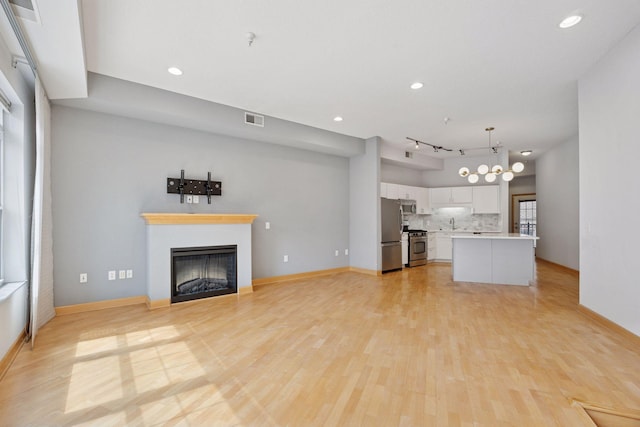 308 18th St Unit 101, Minneapolis, MN 55404 - unfurnished living room featuring baseboards, light wood-type flooring, a fireplace, and visible vents