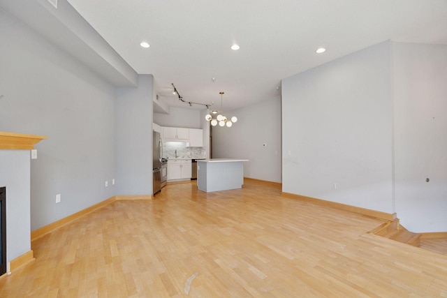 308 18th St Unit 101, Minneapolis, MN 55404 - unfurnished living room featuring baseboards, a notable chandelier, light wood-style floors, recessed lighting, and a glass covered fireplace