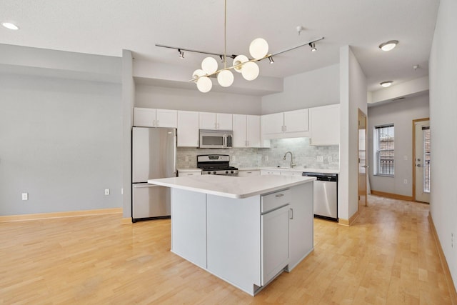 308 18th St Unit 101, Minneapolis, MN 55404 - kitchen featuring rail lighting, tasteful backsplash, a kitchen island, appliances with stainless steel finishes, and light countertops