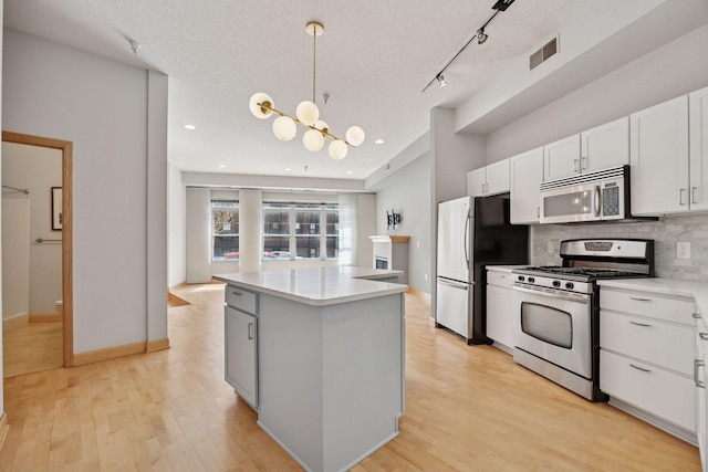 308 18th St Unit 101, Minneapolis, MN 55404 - kitchen with tasteful backsplash, white cabinetry, a kitchen island, visible vents, and stainless steel appliances