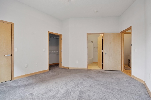 308 18th St Unit 101, Minneapolis, MN 55404 - unfurnished bedroom featuring carpet floors, baseboards, a walk in closet, and connected bathroom