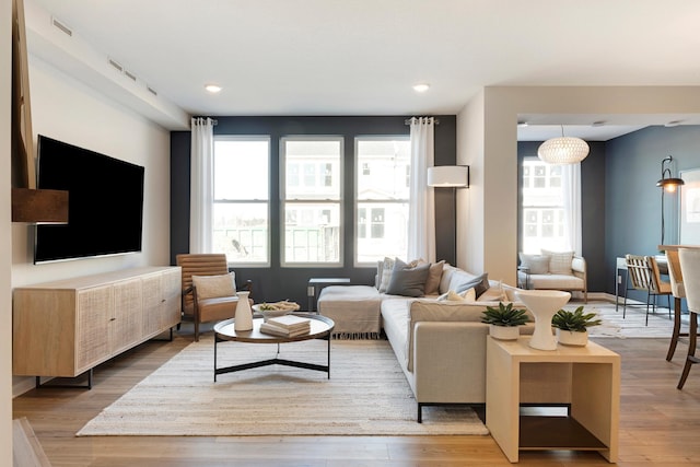 living area with recessed lighting, wood finished floors, visible vents, and baseboards