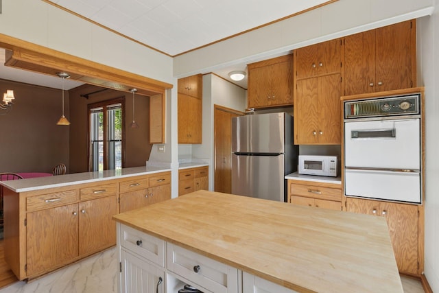 kitchen with white appliances, wood counters, light marble finish flooring, a peninsula, and decorative light fixtures