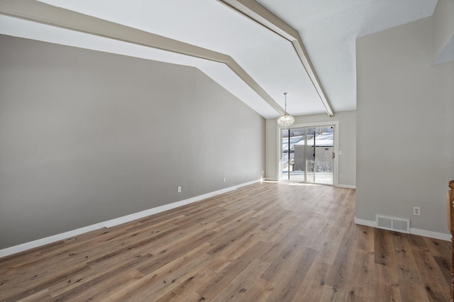 unfurnished living room featuring visible vents, lofted ceiling with beams, wood finished floors, baseboards, and a chandelier