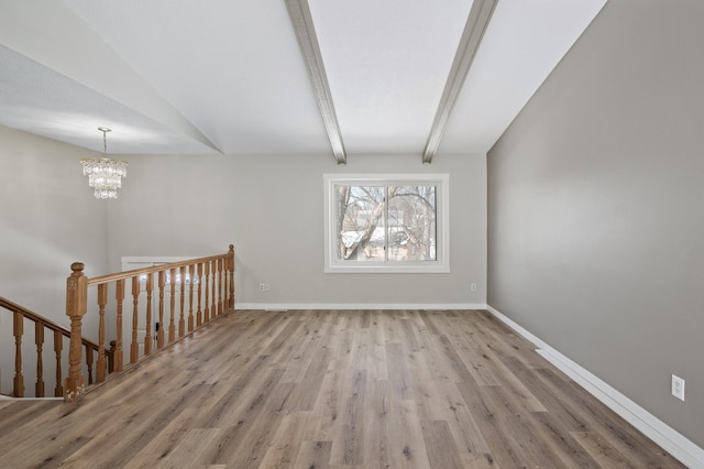 empty room featuring a notable chandelier, vaulted ceiling with beams, baseboards, and wood finished floors