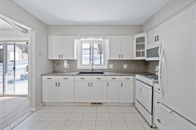 kitchen with visible vents, a sink, white appliances, white cabinets, and decorative backsplash