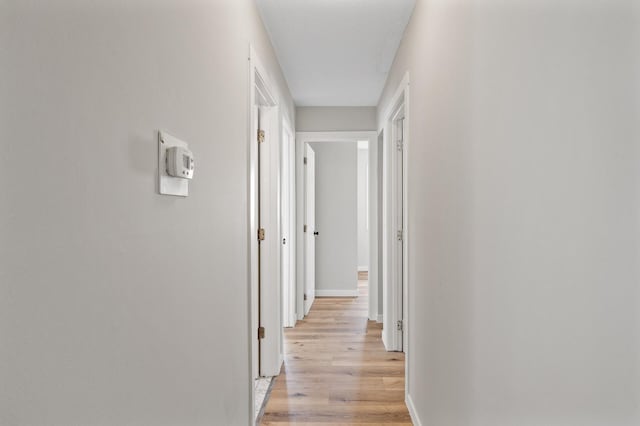 corridor with baseboards and light wood-style floors