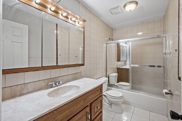 full bathroom with vanity, visible vents, tile walls, toilet, and tile patterned floors