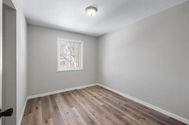 empty room featuring wood finished floors, baseboards, and a textured ceiling