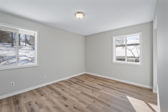 spare room with baseboards and wood finished floors