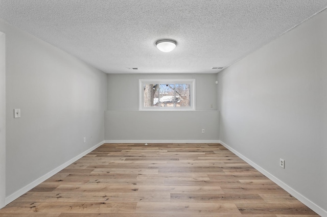 unfurnished room with visible vents, baseboards, light wood finished floors, and a textured ceiling