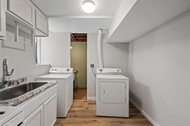 laundry room with a sink, cabinet space, light wood-style floors, and washing machine and clothes dryer