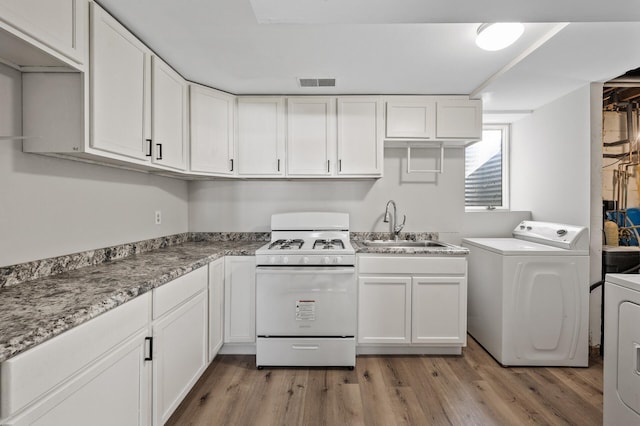 clothes washing area with visible vents, laundry area, light wood-style flooring, a sink, and washer and clothes dryer