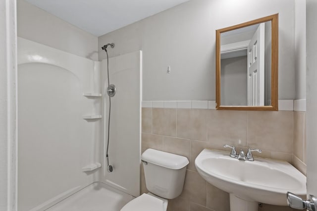 bathroom with a sink, tile walls, toilet, and walk in shower