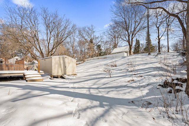 yard covered in snow with an outbuilding, a shed, and a deck