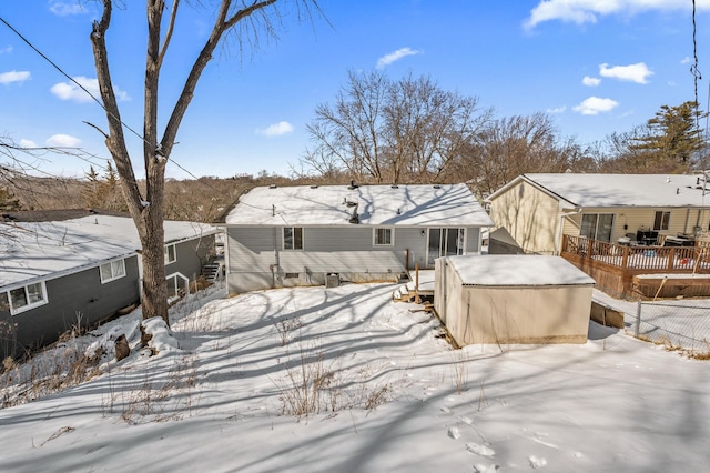 snow covered house featuring a deck and fence