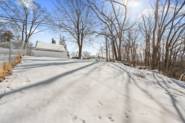 snowy yard with an outbuilding and fence