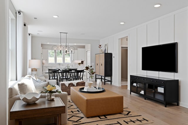 living room with light wood-type flooring, an inviting chandelier, and recessed lighting