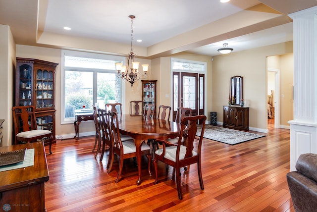 dining area featuring a wealth of natural light, light wood-type flooring, and decorative columns