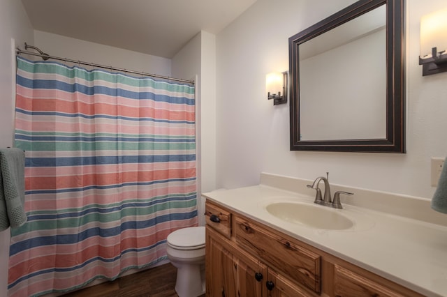 bathroom featuring toilet, a shower with shower curtain, wood finished floors, and vanity