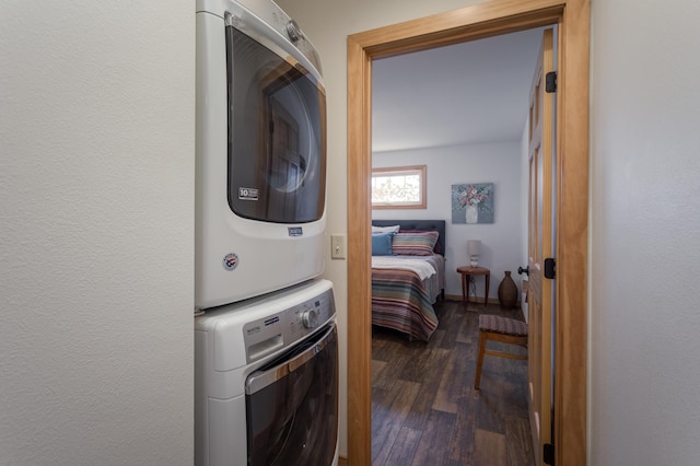 clothes washing area with laundry area, dark wood finished floors, stacked washer and clothes dryer, and baseboards