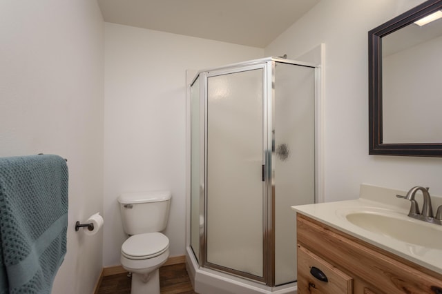 full bathroom featuring toilet, wood finished floors, a shower stall, and vanity