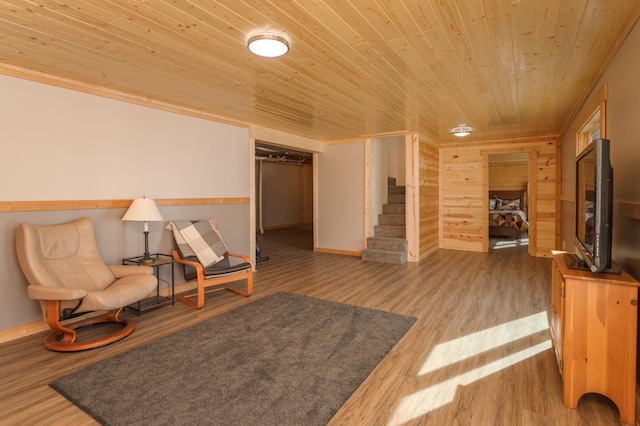 living area featuring wood walls, stairway, wooden ceiling, and wood finished floors