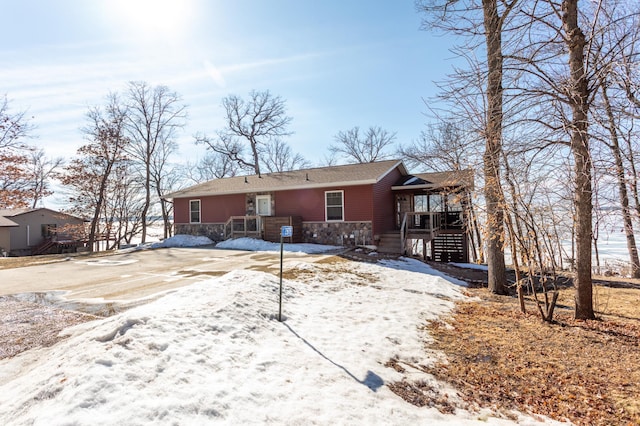 snow covered back of property featuring stone siding