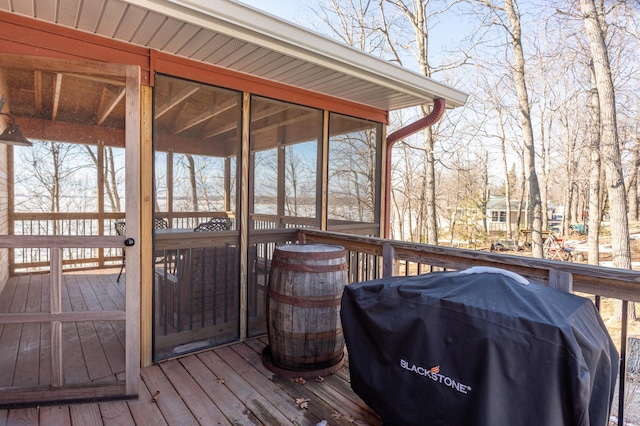 wooden terrace with a sunroom and area for grilling