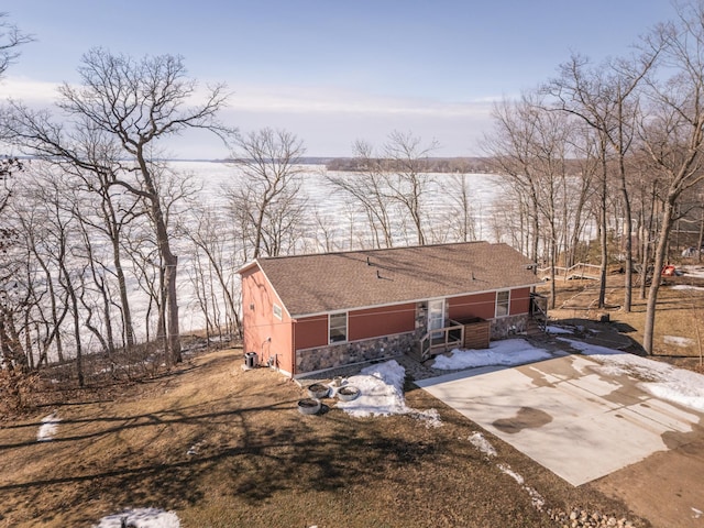 view of front of house featuring driveway, a shingled roof, and stone siding