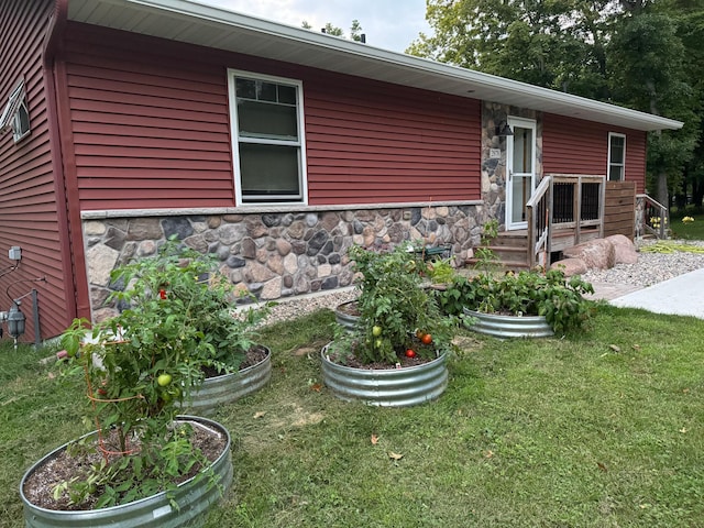 exterior space with stone siding, a vegetable garden, and a front yard