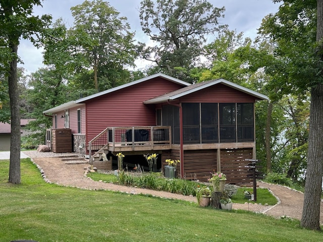 rear view of property featuring a sunroom, a yard, and a wooden deck