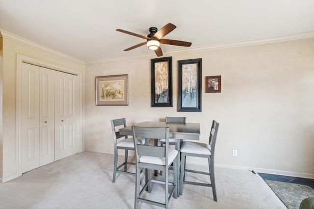 dining space featuring a ceiling fan, carpet, crown molding, and baseboards