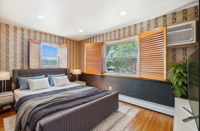 bedroom with wallpapered walls, multiple windows, and baseboard heating