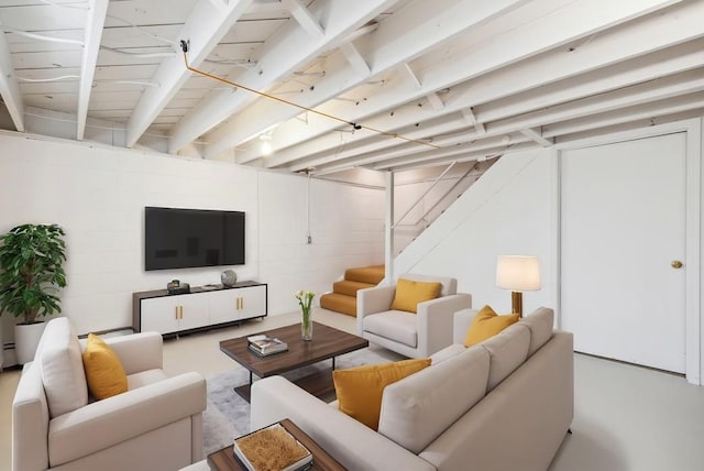 living area featuring finished concrete flooring, stairs, and concrete block wall