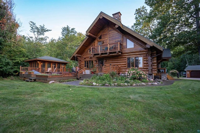 back of property with a chimney, a yard, log exterior, and a balcony