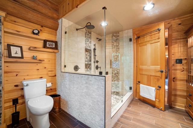 full bathroom featuring toilet, wood walls, a shower stall, and wood tiled floor