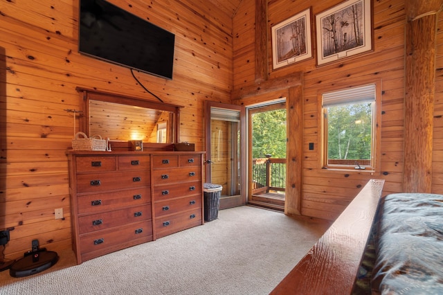 bedroom featuring light carpet, wood walls, a towering ceiling, and access to exterior