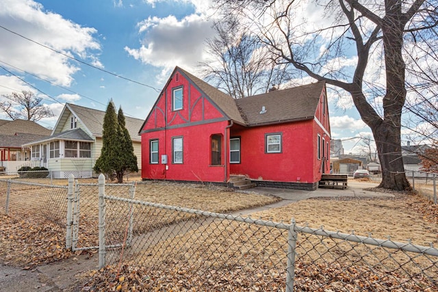 view of front of property with a fenced front yard, stucco siding, roof with shingles, and a sunroom