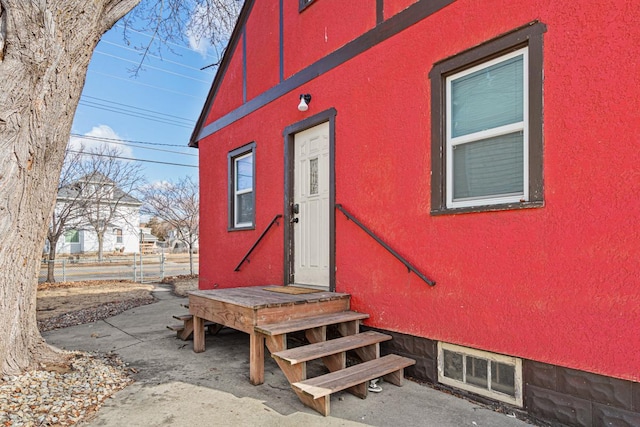 property entrance featuring stucco siding and fence