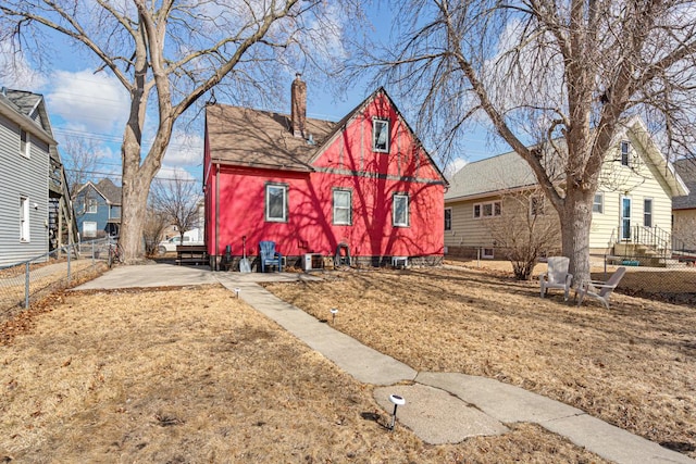 view of front of property featuring central air condition unit, fence, roof with shingles, and a chimney