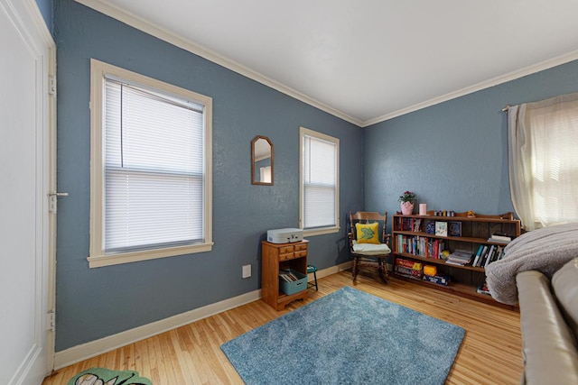 sitting room featuring crown molding, wood finished floors, baseboards, and a textured wall