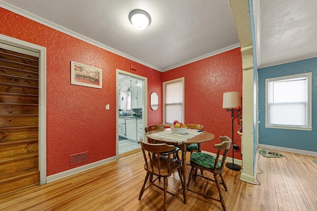 dining room featuring crown molding, a textured wall, and visible vents