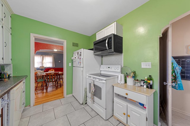 kitchen featuring arched walkways, visible vents, white appliances, and decorative backsplash