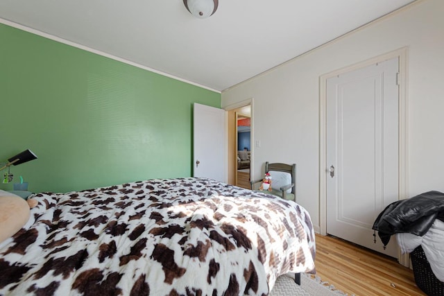 bedroom with crown molding and light wood-style flooring